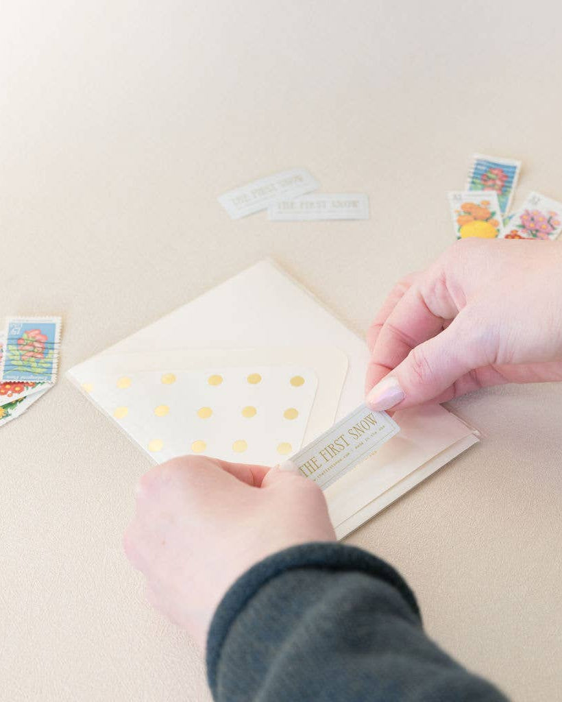 Person applying a gold sticker to a card with other cards in the background