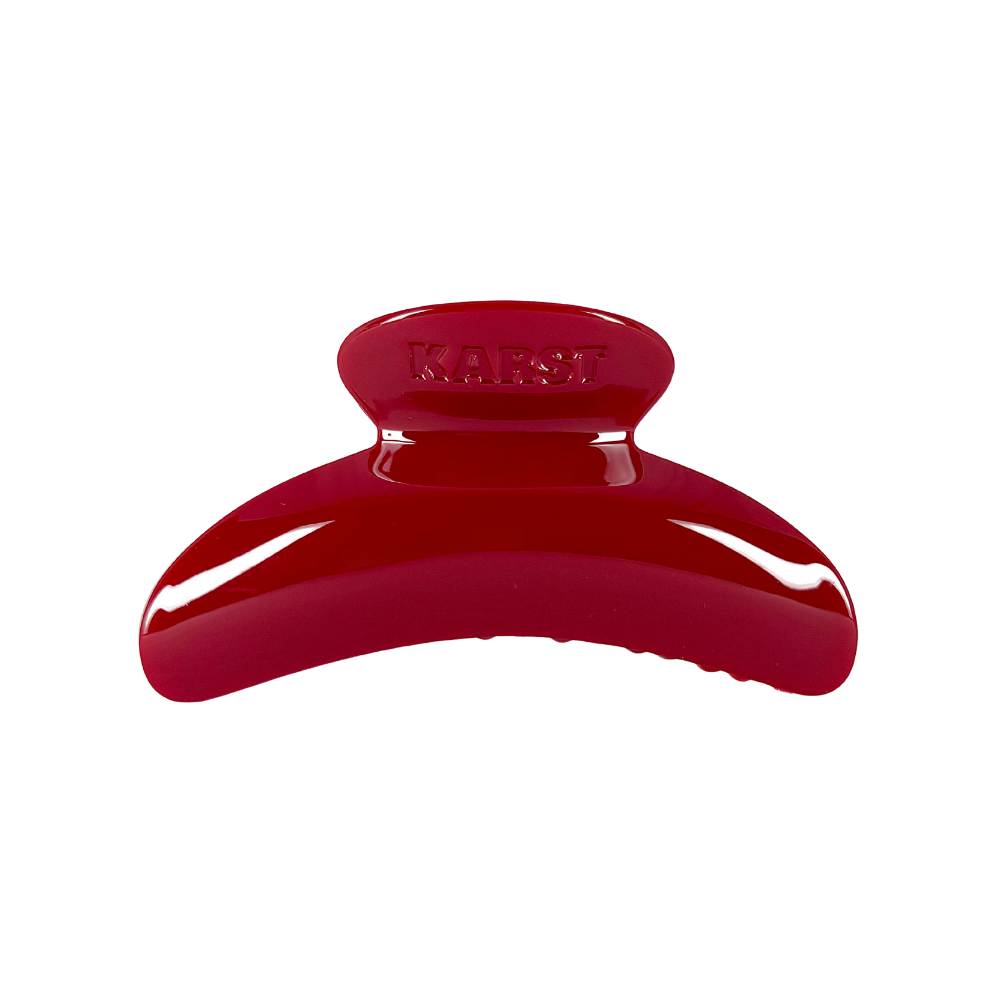 A shiny, bright red SuperClip Hair Claw — Maraschino: No Charm Eyelet (Standard) from Karst Essentials is displayed against a plain white background, with the brand’s name embossed on top.