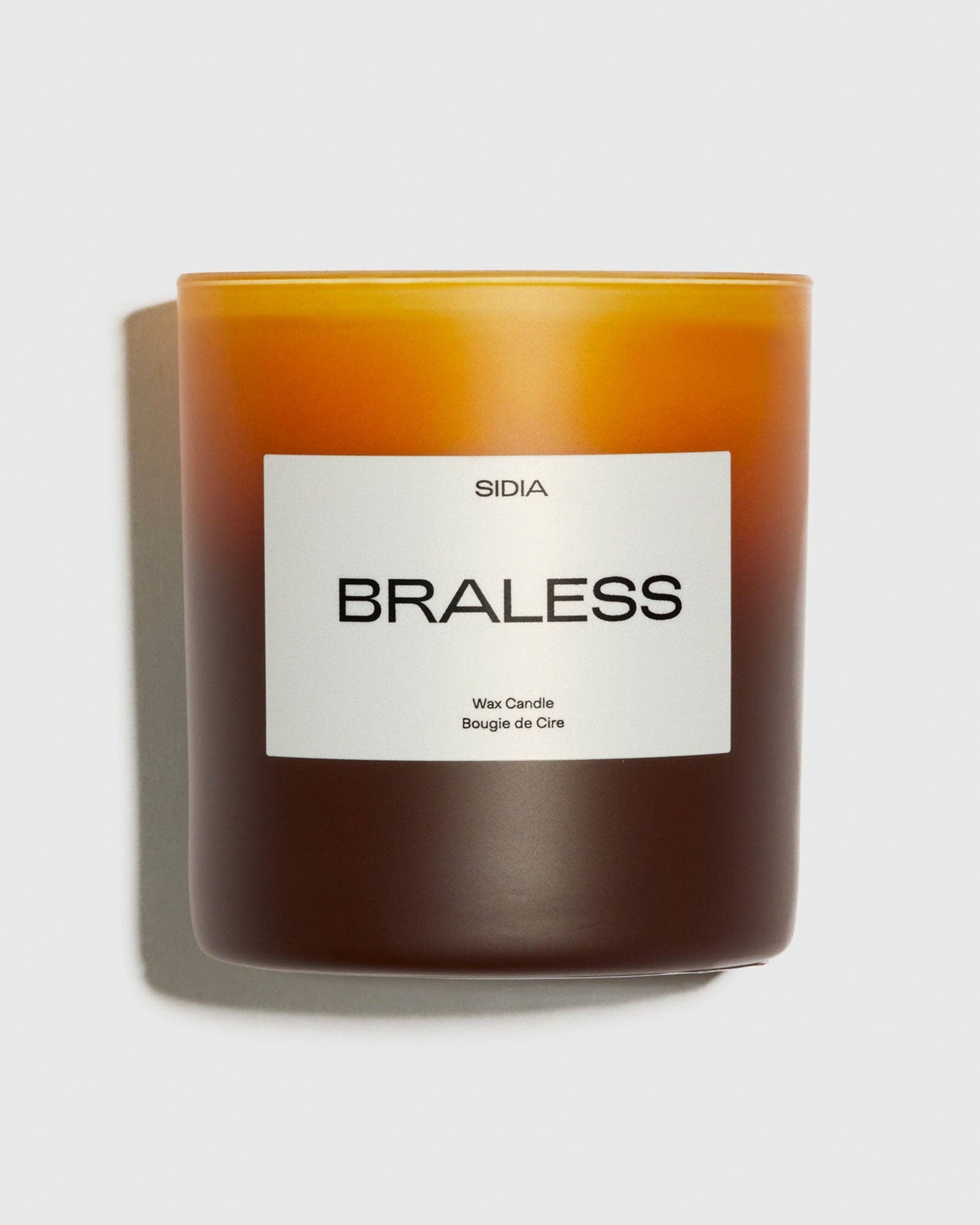 Candle with a label reading &#39;Braless&#39; on a light gray background