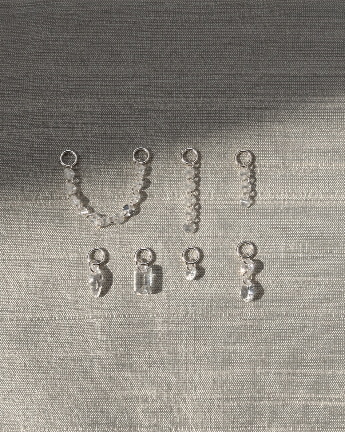 Noa Sapphire Earring Charms by Mod + Jo featuring seven silver hoop charms with multifaceted lab-grown white sapphire beads in various shapes and chain lengths.