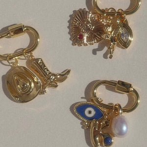 Gold necklace enhancers with various charms on a white background