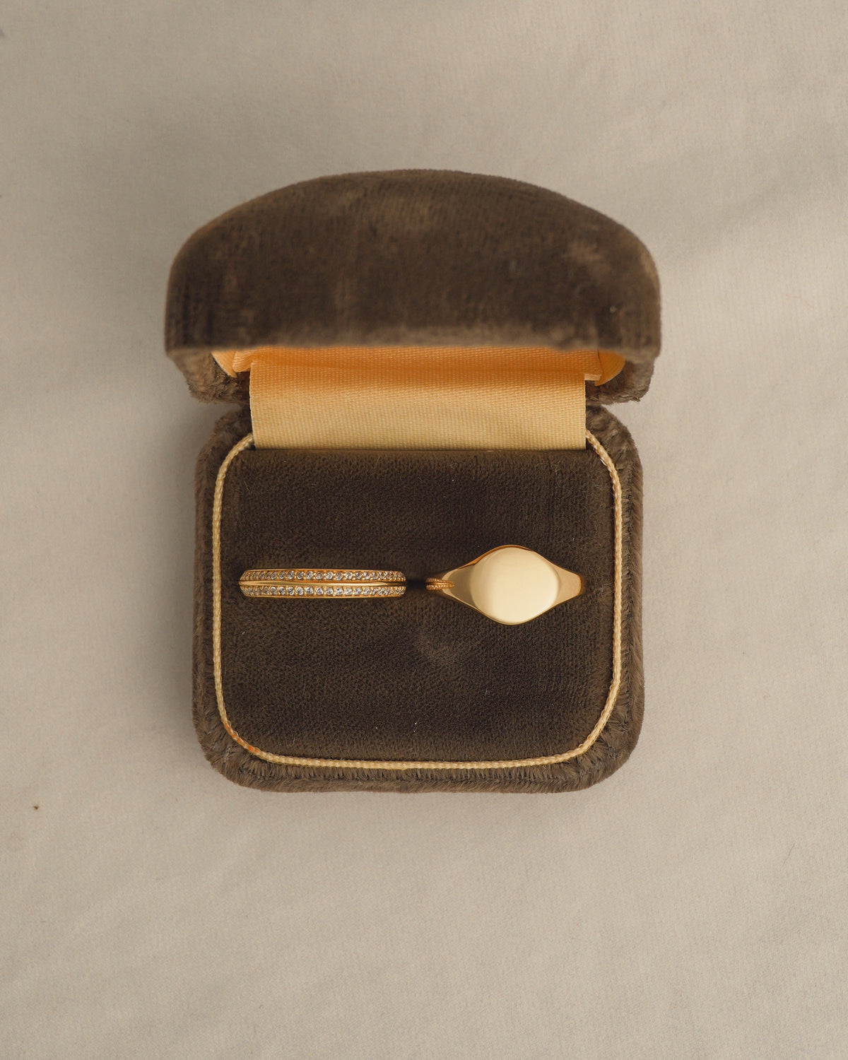 A gold Mariah + Tessa Set, consisting of a Mariah Pave Knife Edge Band and a gold signet ring, resting in an open jewelry box.