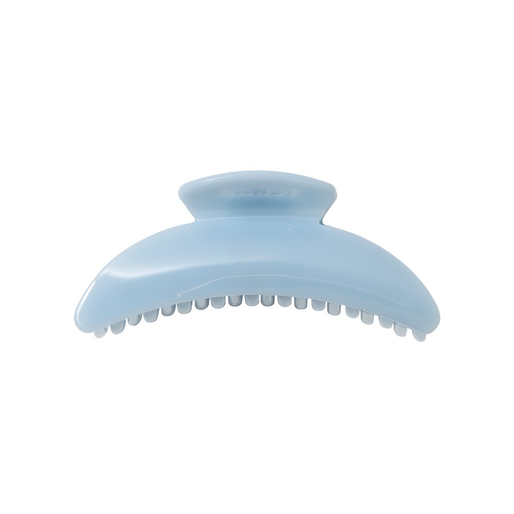 The Slim Hair Claw Clip — Mist by Karst Essentials is a slim, sky blue cellulose acetate clip with a curved shape and interlocking teeth, displayed on a white background.