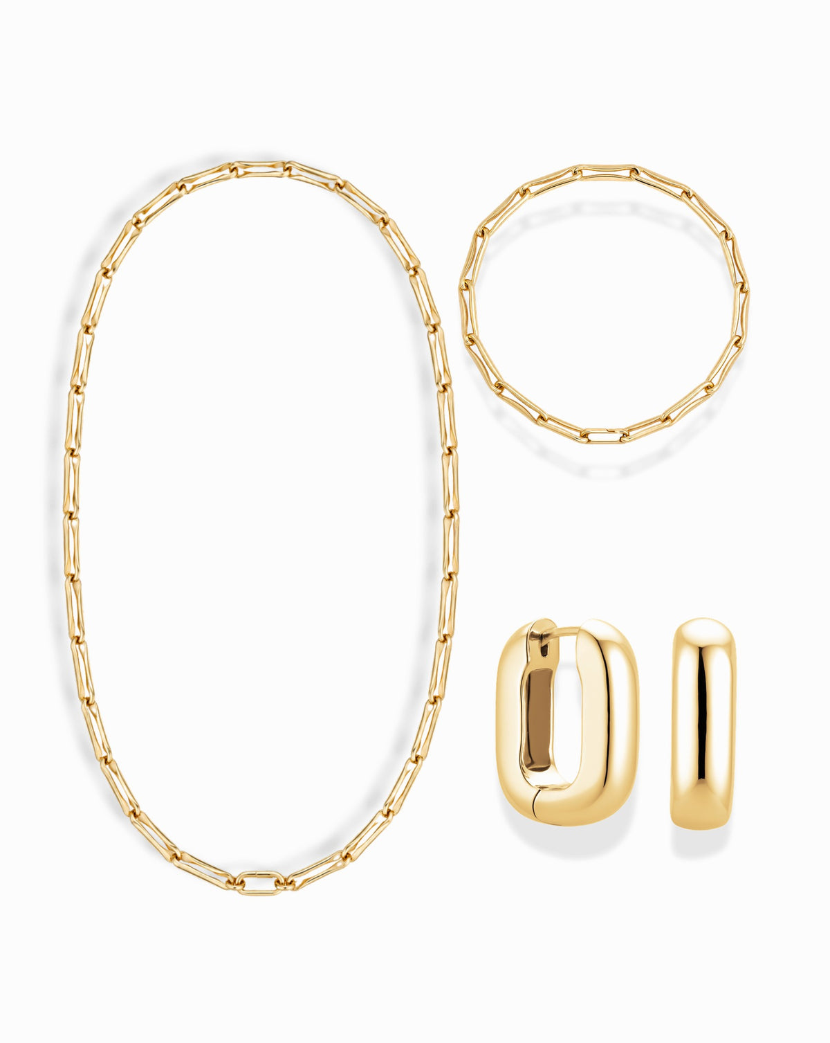 The Mod + Jo Barely-There Trio Set featuring an elongated link necklace, a matching bracelet, and petite gold hoop earrings.