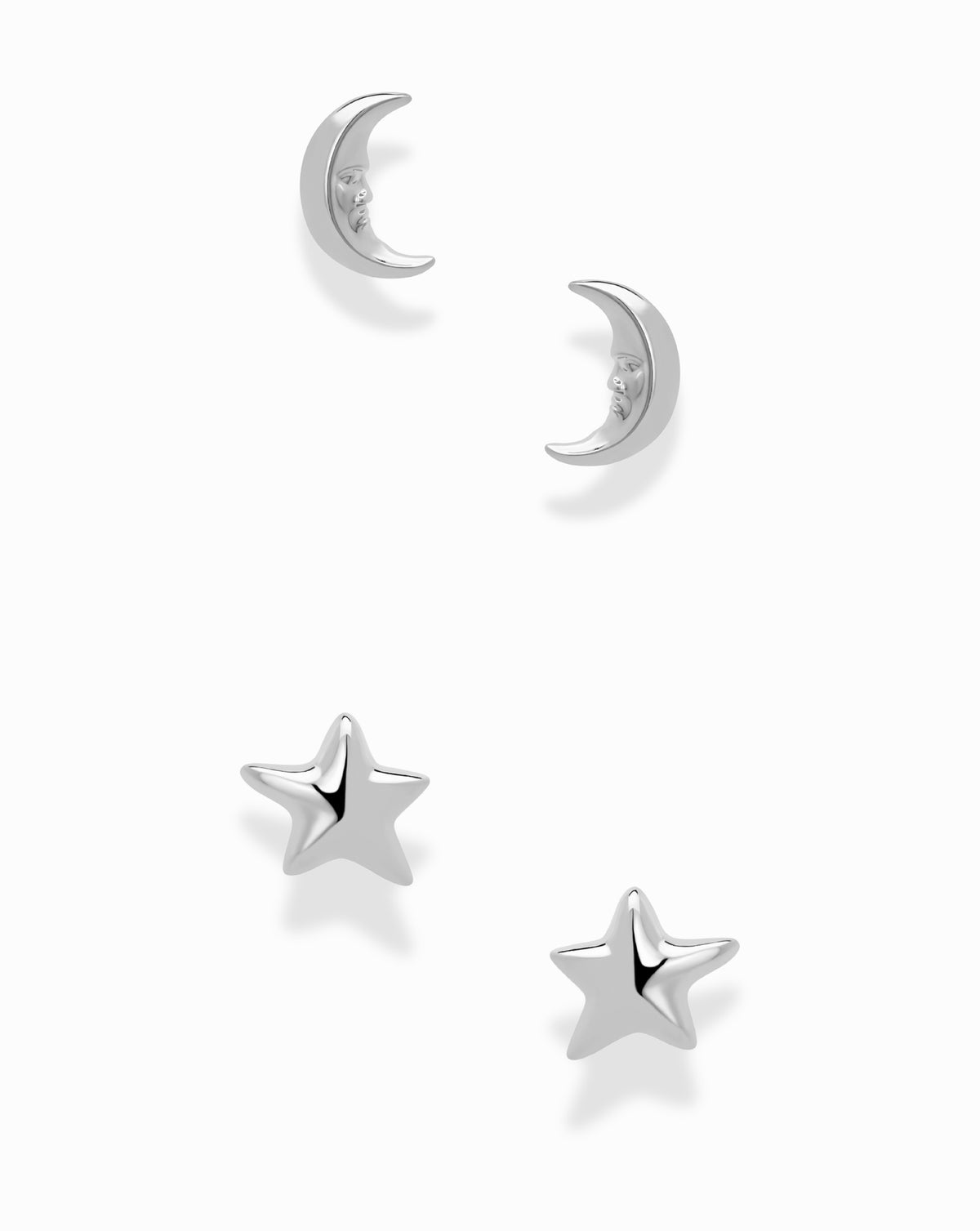 A Mod + Jo Celestial Studs Set featuring two silver moon stud earrings with faces and two silver star stud earrings.