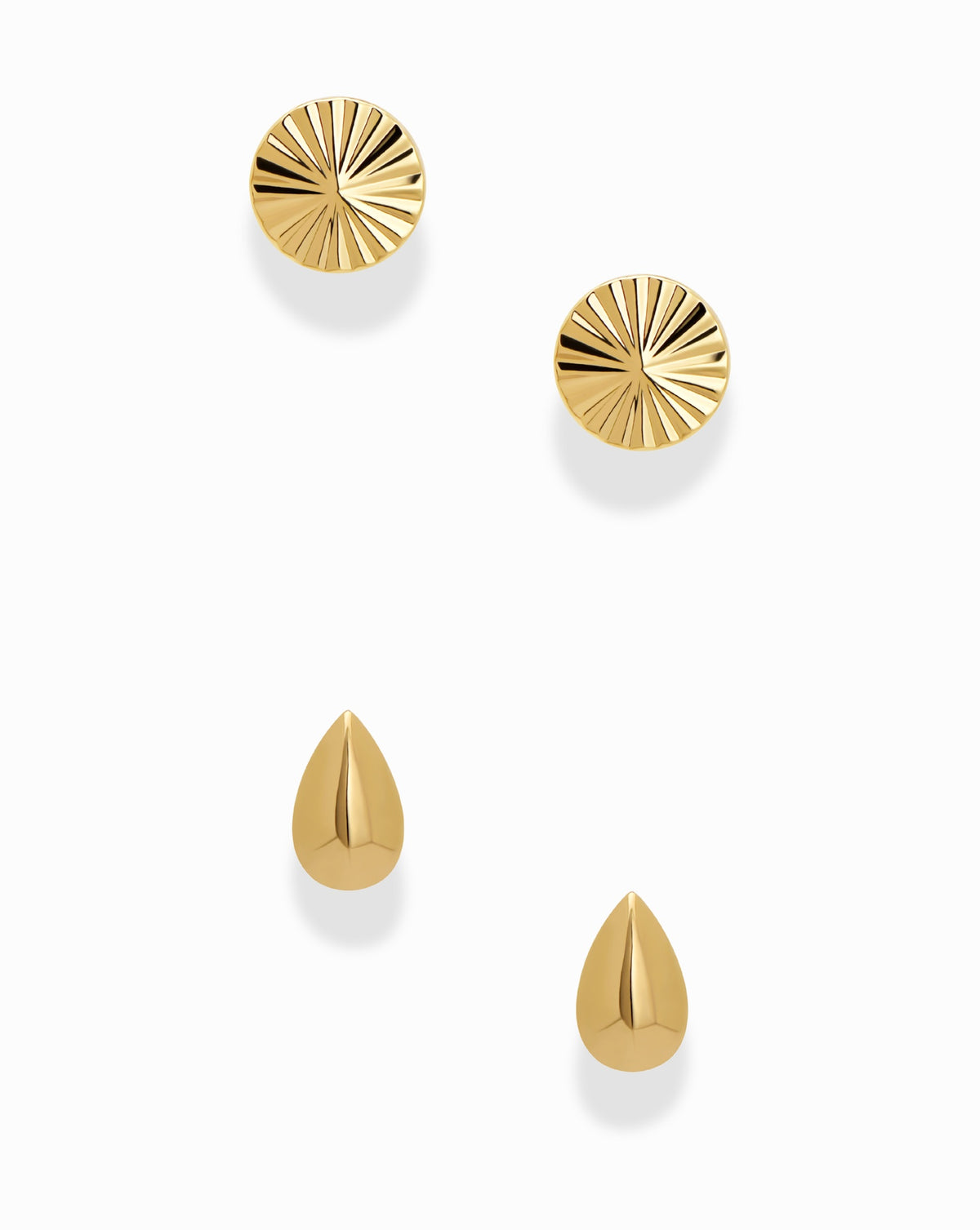 Dela + Uma Set featuring two gold-toned stud earrings with a circular, radiating sunburst pattern and two fluted, teardrop-shaped stud earrings.