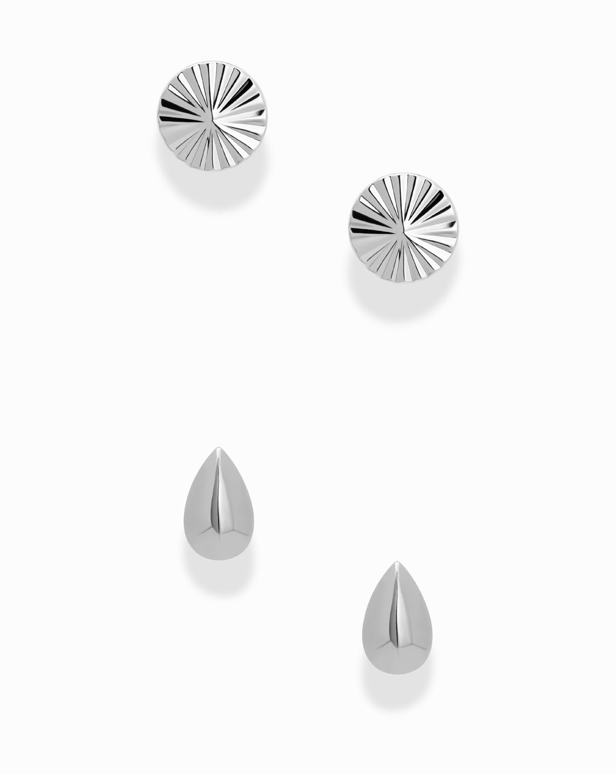 Dela + Uma Set featuring two round, fluted stud earrings paired with two smooth, teardrop-shaped stud earrings.