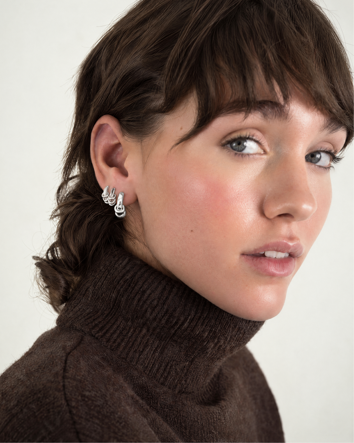 A person wearing a pair of interlocking silver Levi Huggies.