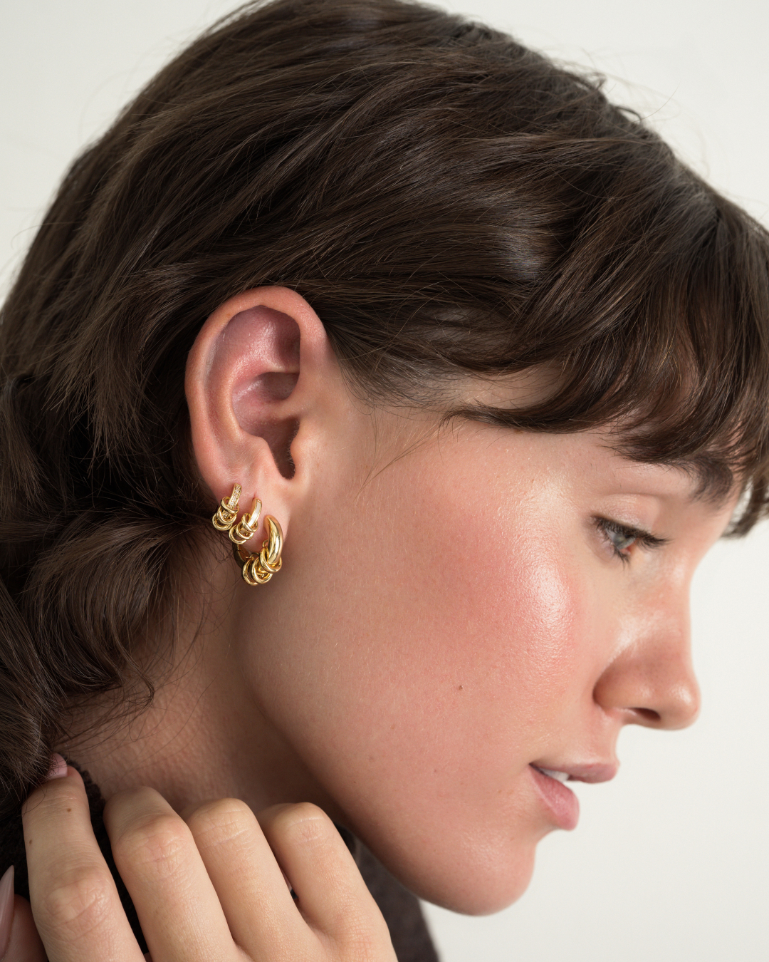 A person wearing two linked Levi Huggies in their earlobe.