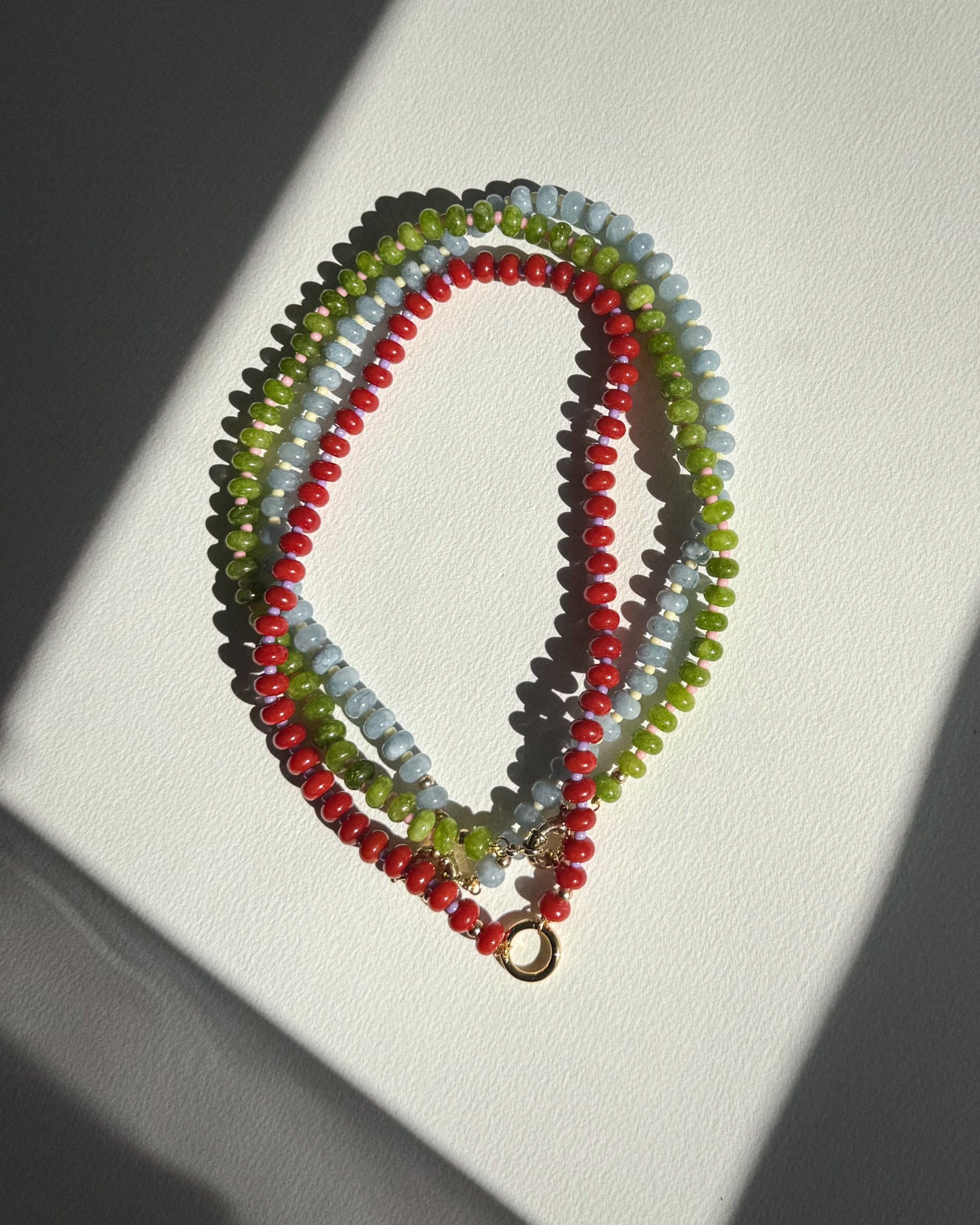 Stack of colorful beaded necklaces on a white surface
