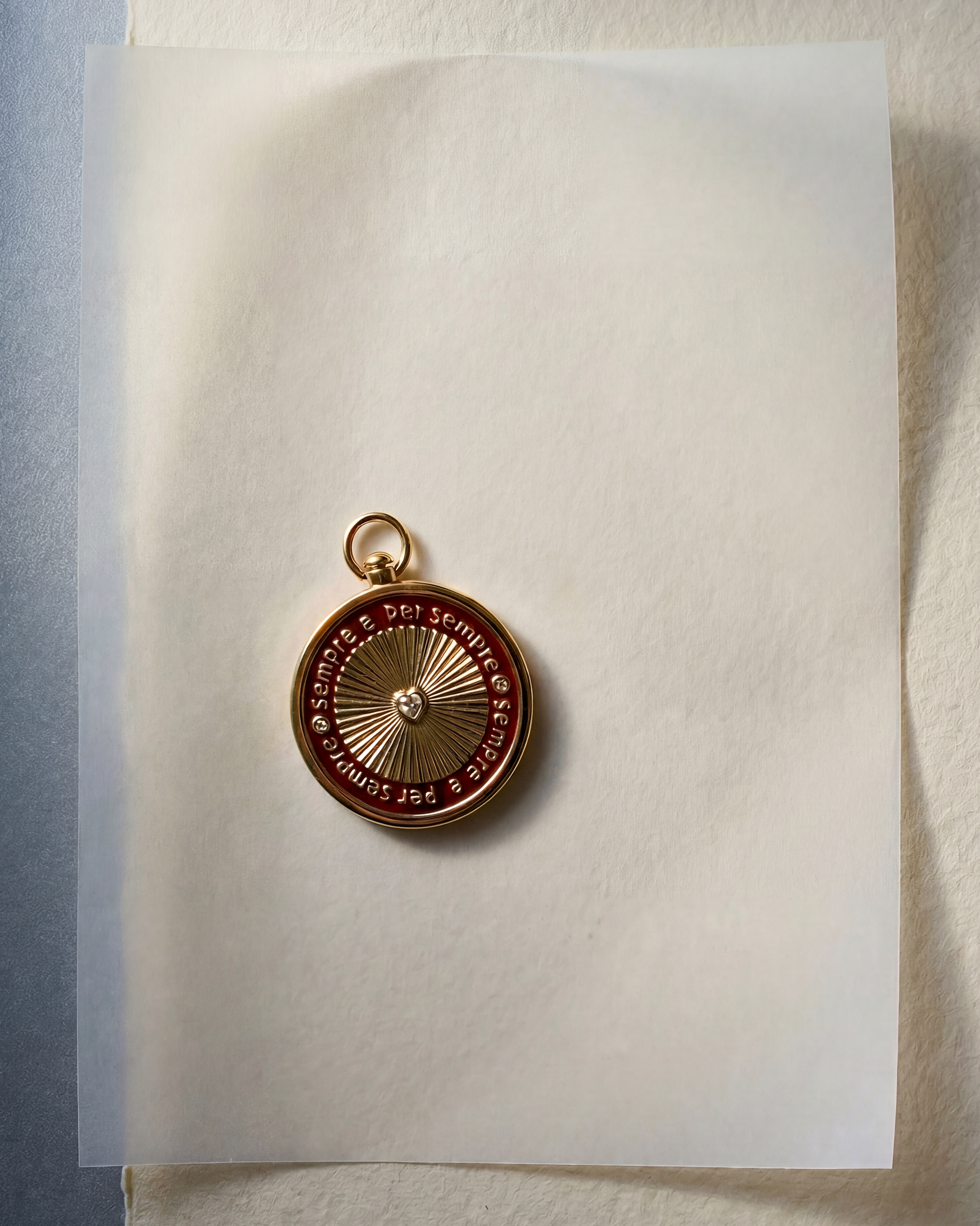 Gold pendant laying on white paper with a light blue background