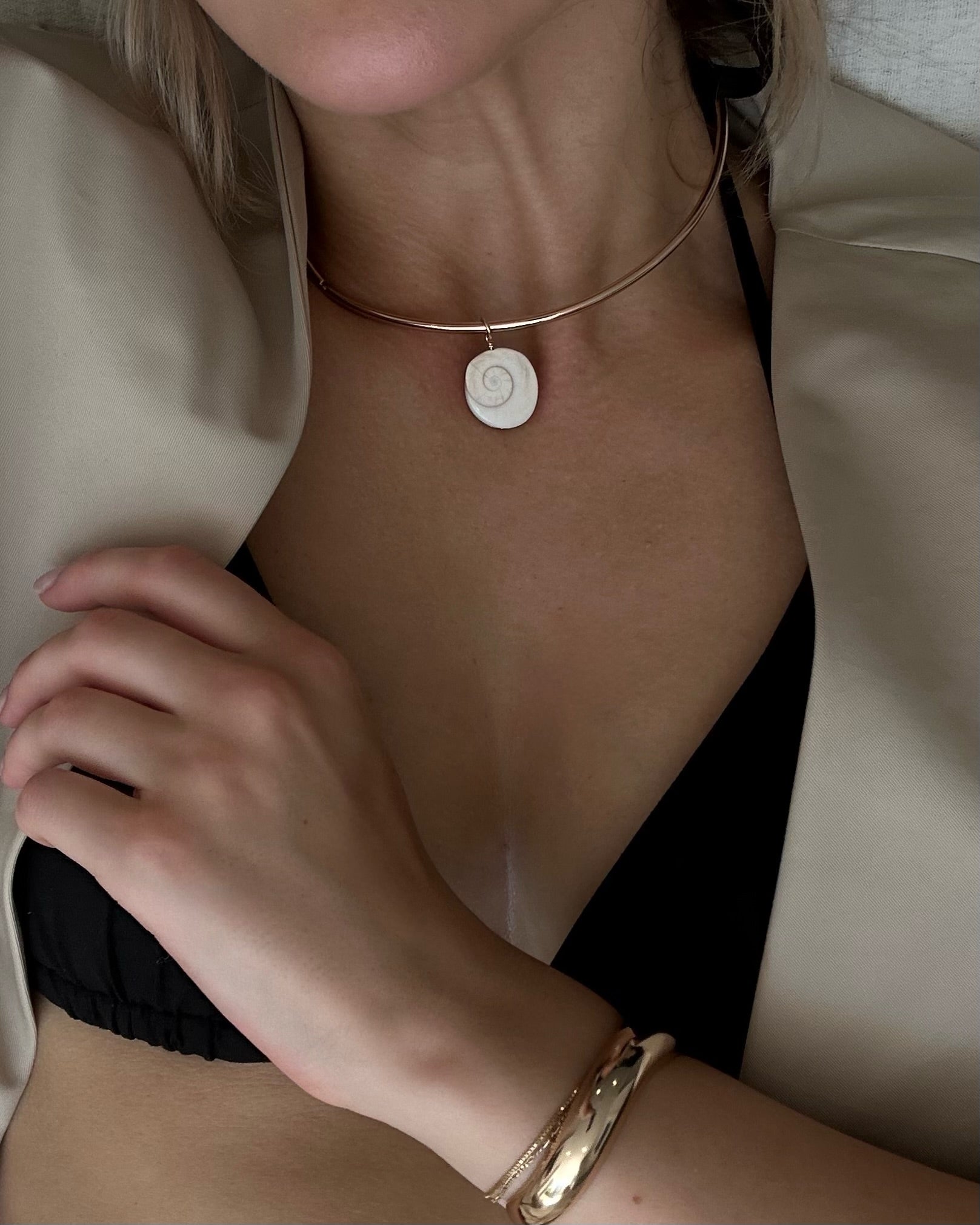 Necklace with a circular pendant worn by a person, with a neutral background