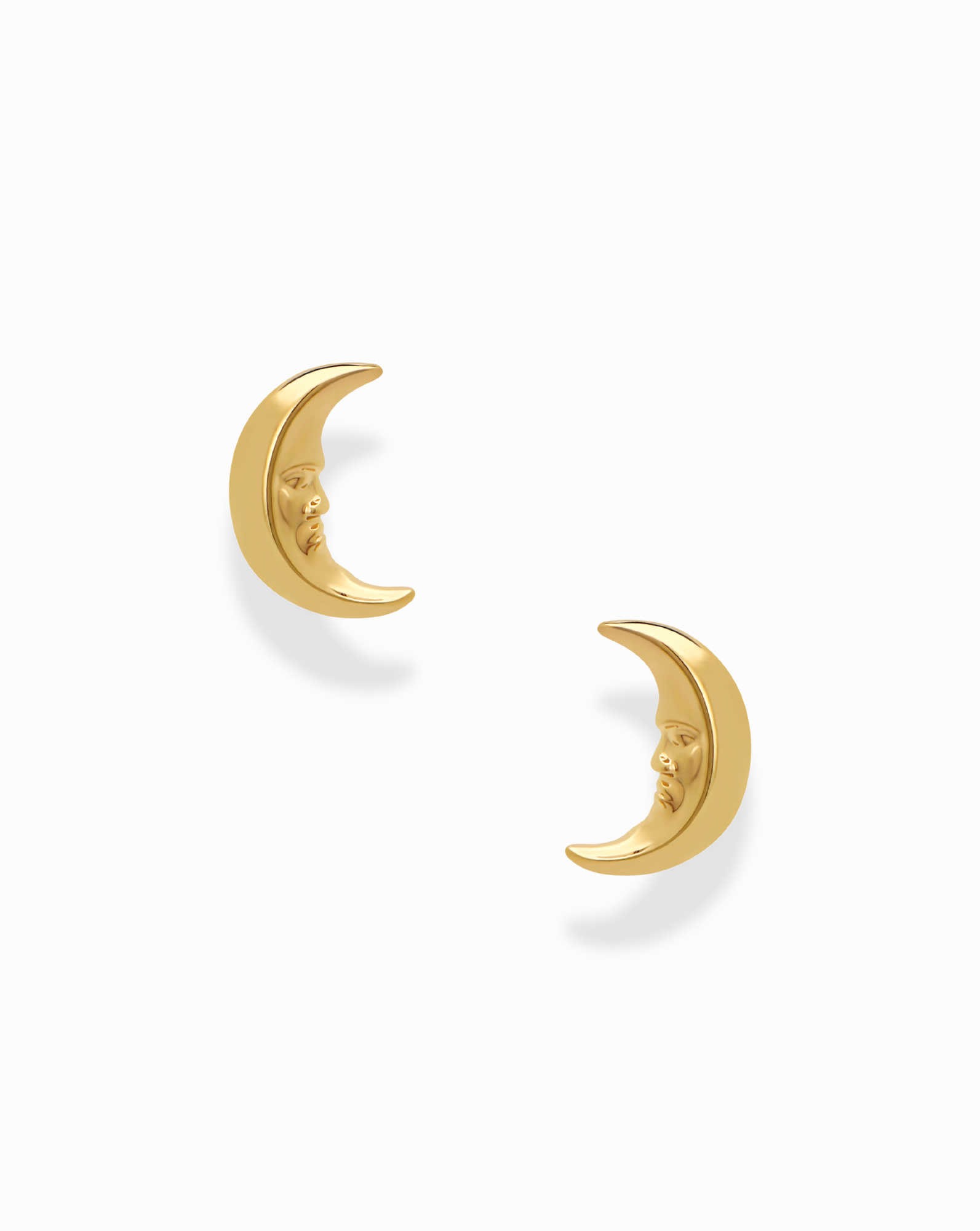 The Archie Moon Studs by Mod + Jo are a pair of gold plated earrings, each adorned with a delicately carved crescent moon face. Displayed on a white background, these whimsical studs make an enchanting addition to any celestial jewelry collection.
