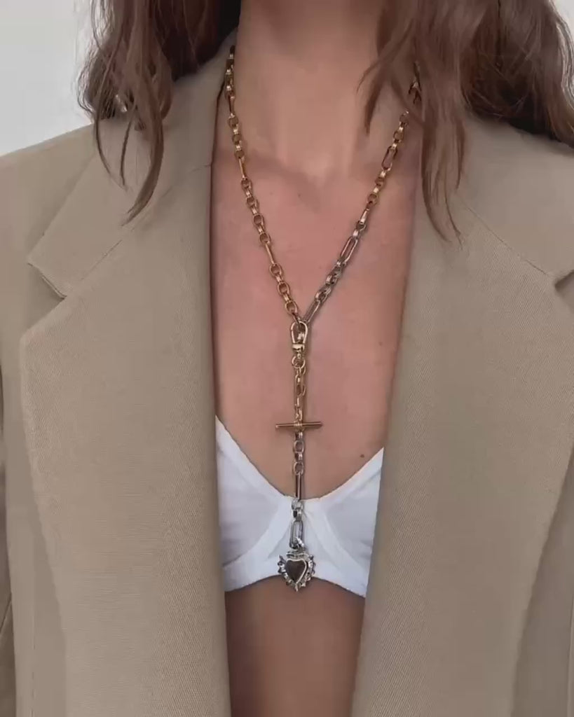 A close up of a woman wearing a long lariat necklace with charms