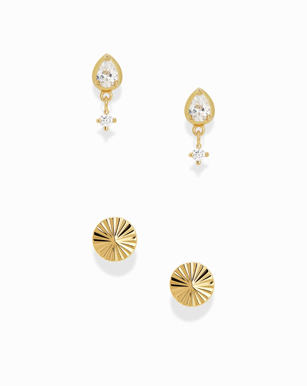 The Quinn + Dela Set featuring two gold earrings with pear-shaped crystals and dangling round stones, and two gold Quinn Studs with sunburst-style radial textures.