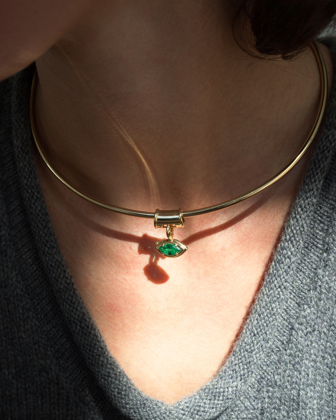 A gold-plated Mod + Jo Tash Charm Enhancer collar necklace featuring a small, marquise-shaped green gemstone charm shaped like an eye.