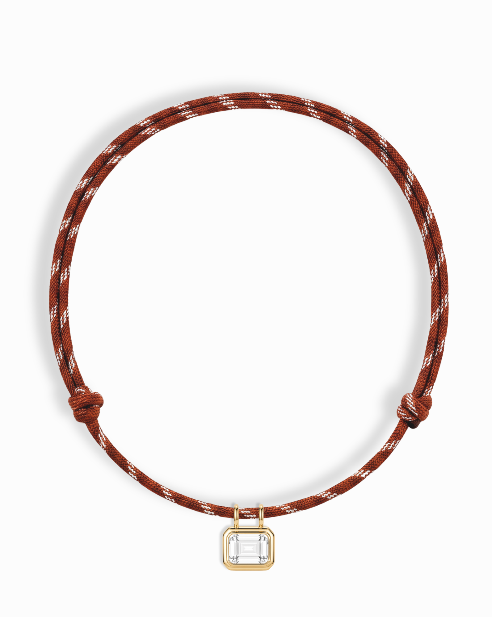The Mod + Jo Tommy Sapphire Pendant Necklace is an adjustable brown and white paracord necklace featuring a gold and clear rectangular pendant at the center, displayed on a white background.