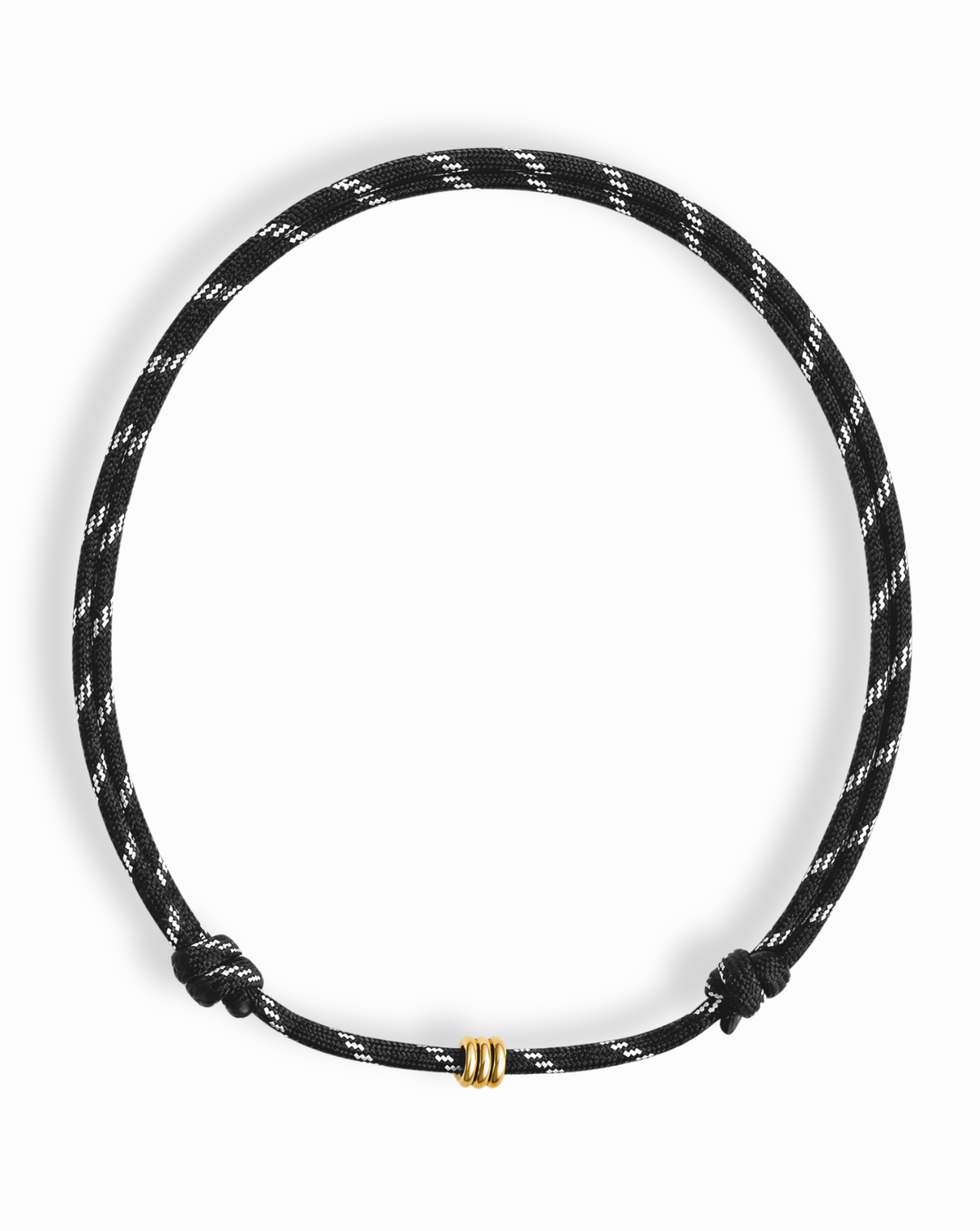 The Tommy Cord Necklace by Mod + Jo features a black paracord design with white diagonal stripes and a small gold-colored ring as its central accent, finished with two knotted ends. Its adjustable style ensures a comfortable fit for any wearer.