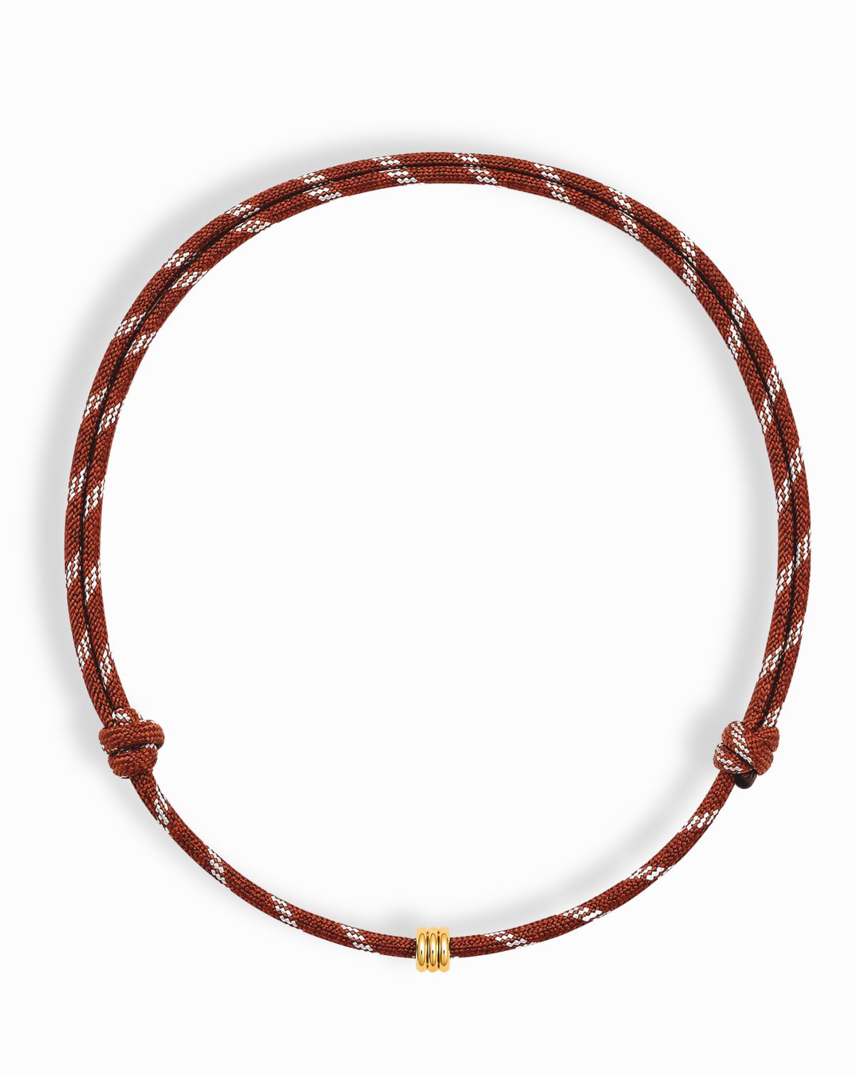 The Mod + Jo Tommy Cord Necklace is a brown and white braided paracord necklace featuring a small gold bead knotted on both sides, accented with gold-plated spacers, and displayed against a white background.